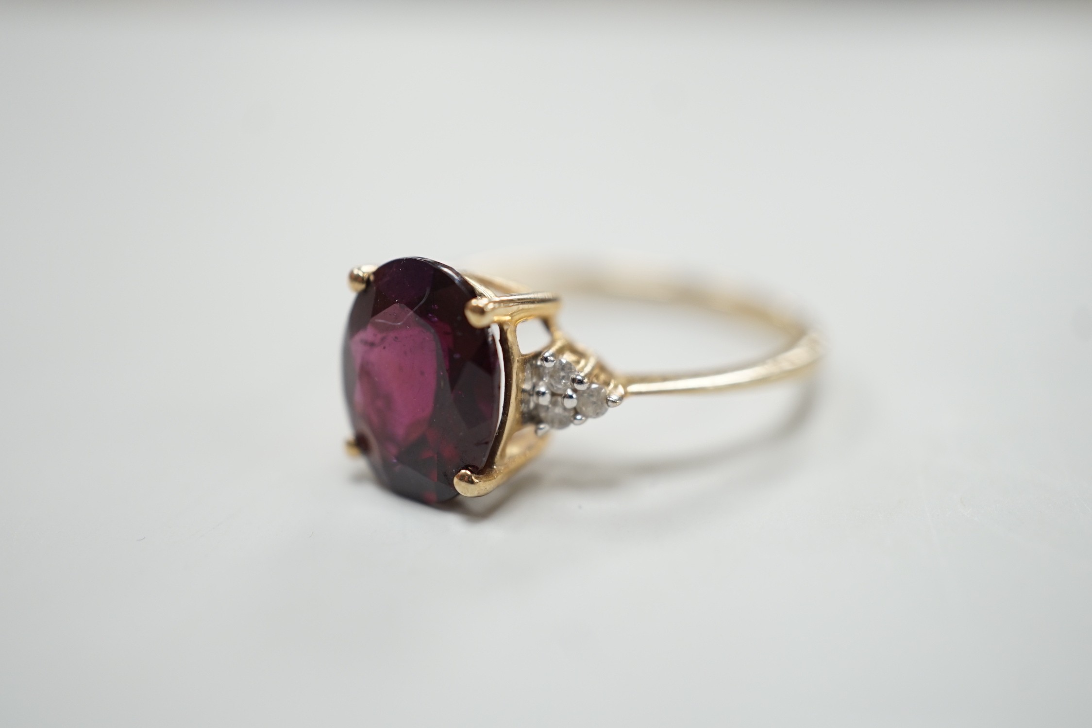 A modern 9ct gold, single stone oval cut garnet and six stone diamond chip set dress ring, size R/S, gross weight 2.8 grams.